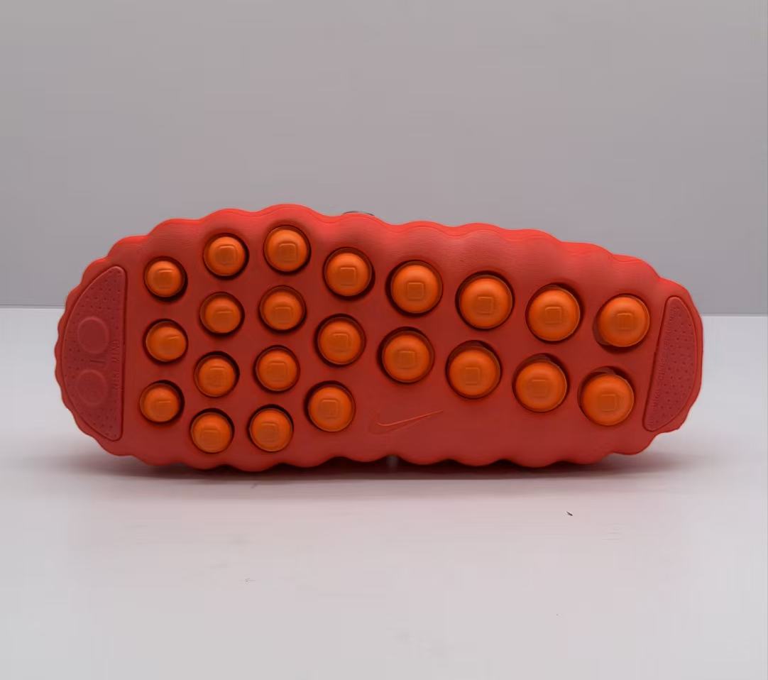 Underside view showing the orange circular traction pods across the orange-red outsole.