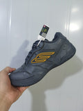 Close-up angled view of a dark grey Balenciaga Hampton sneaker with yellow side detailing and black laces.