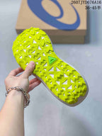 Close view of the bright lime outsole showing a deep, geometric traction pattern and an ASICS shoebox in the background.