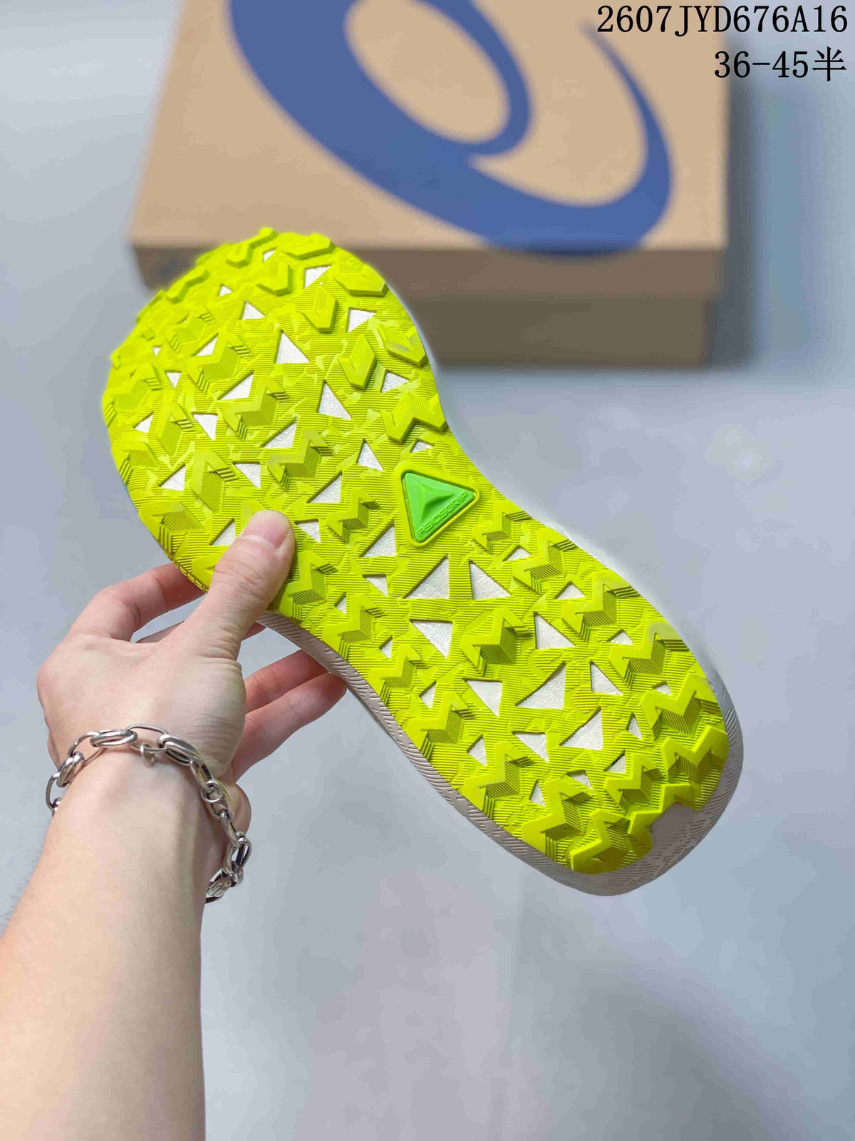 Close view of the bright lime outsole showing a deep, geometric traction pattern and an ASICS shoebox in the background.