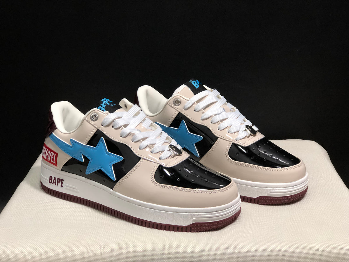 Three-quarter front view highlighting the cream toe and eyestay panels, glossy black sections, blue star emblems, and white laces.