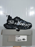 Side view of a black Balenciaga Track sneaker with white graffiti lettering displayed on its shoebox.