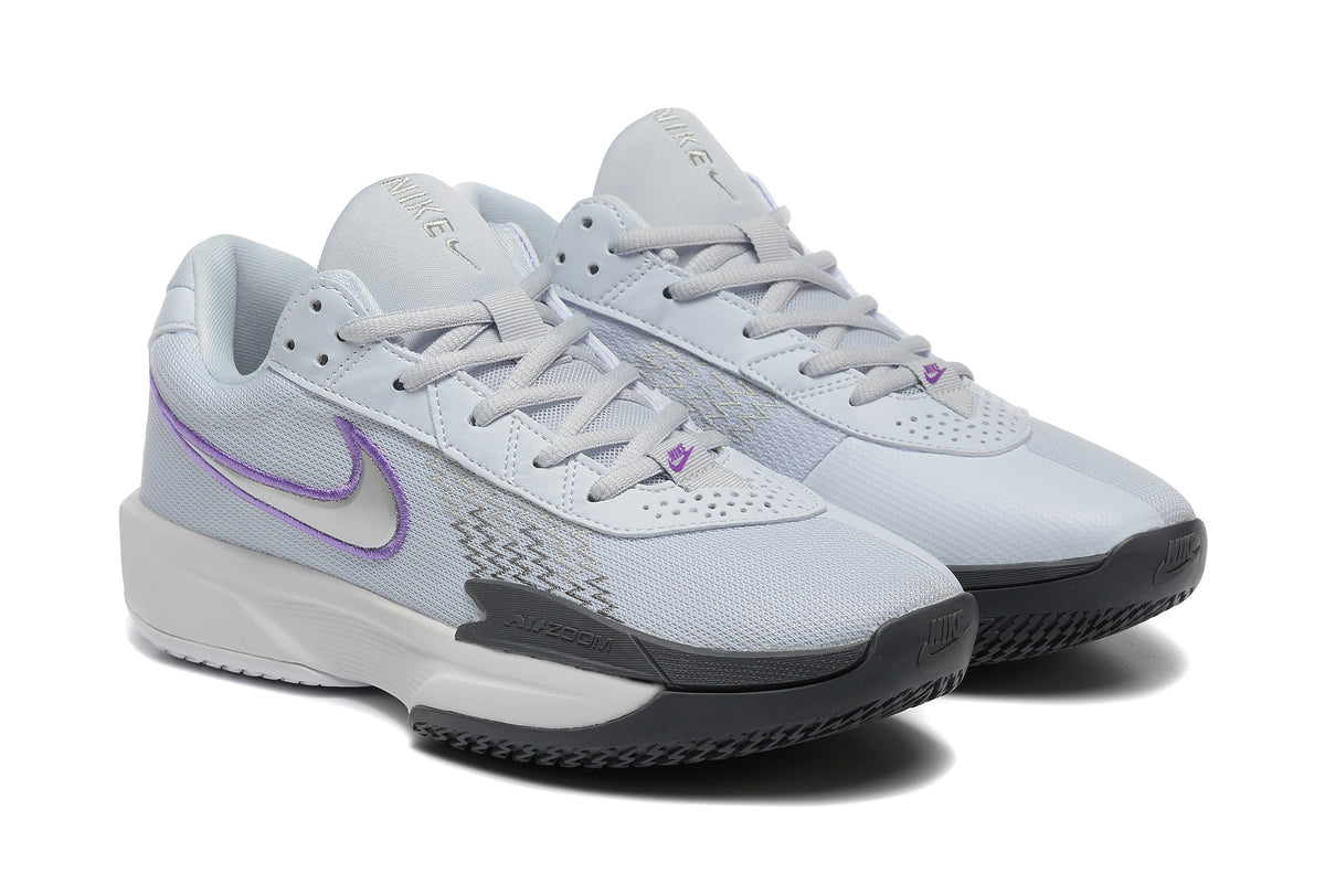 Pair of pale grey Nike tennis shoes with purple Swoosh accents, shown at an angle