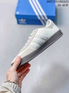 Side profile of the white and gray low-top sneaker showing the three-stripe detailing and dark sole.