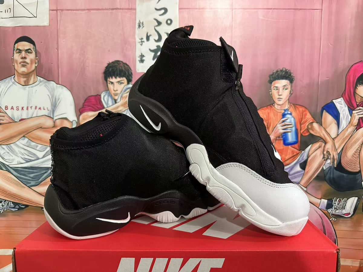 Angled view of black and white high-top Nike basketball sneakers showing the zip-front construction, white forefoot panels, and contrasting outsole.