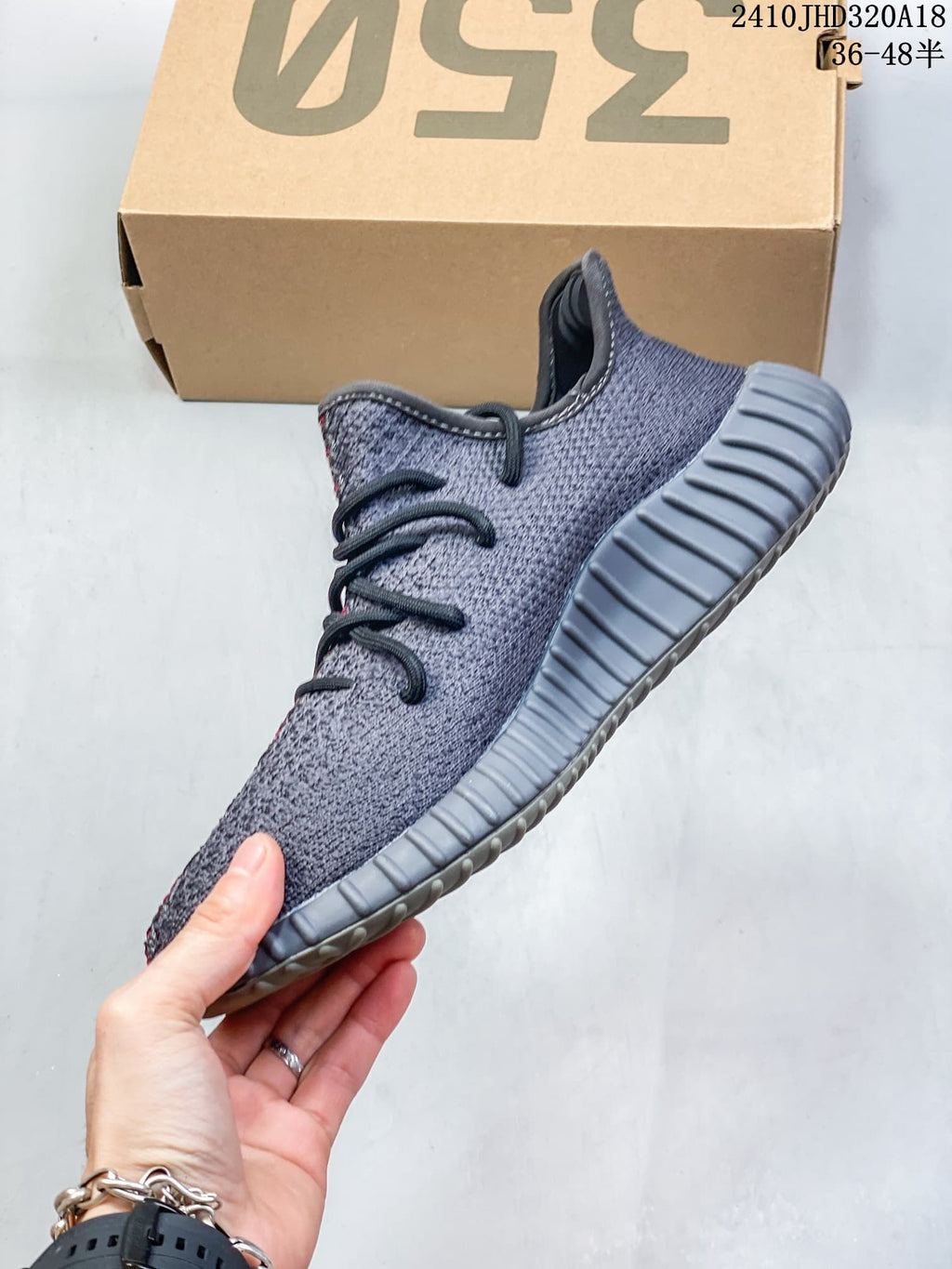 Side view of the gray Adidas Yeezy Boost 350 V2 sneaker showing the textured upper, black laces, and ribbed gray outsole.