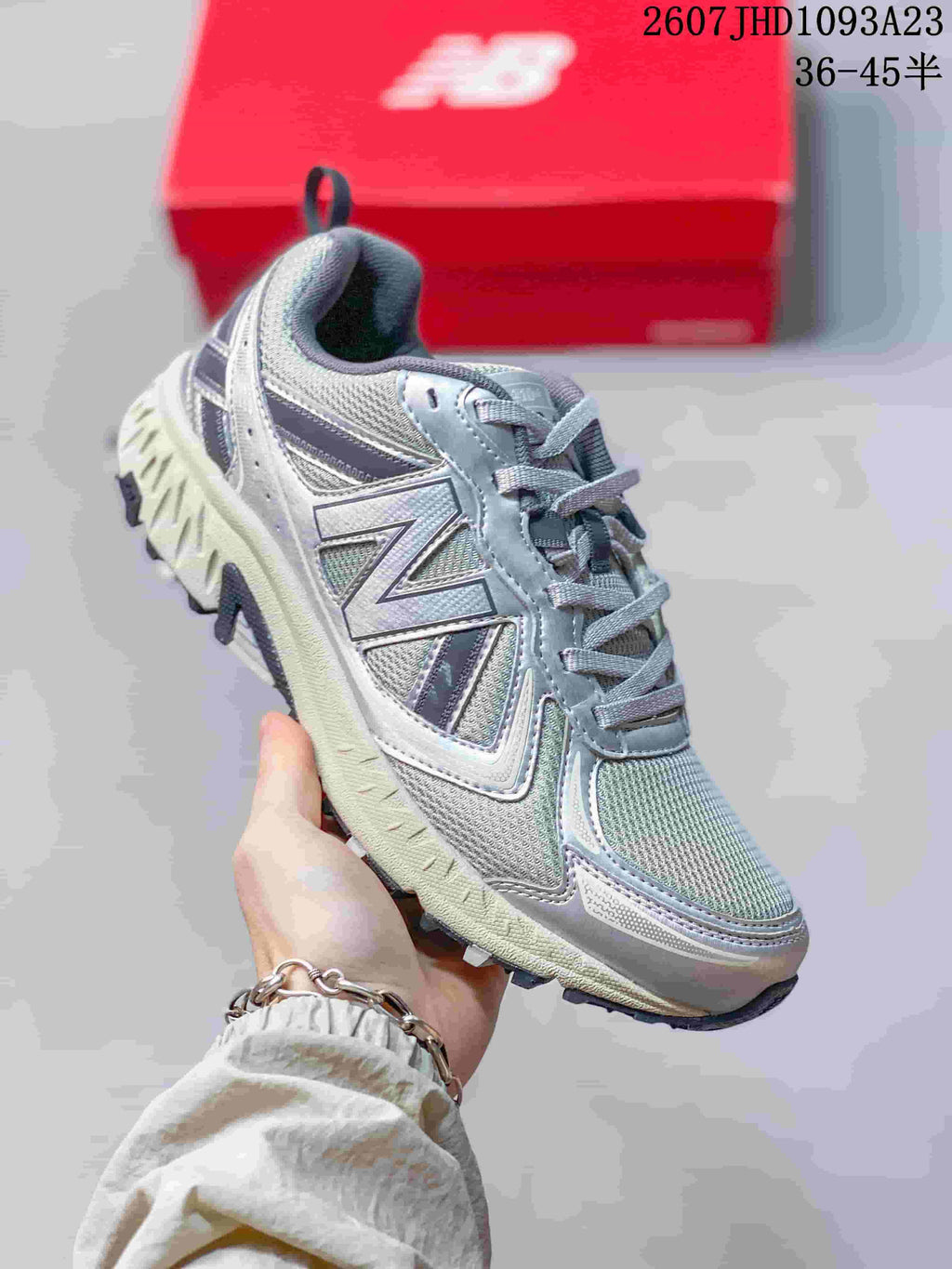 Angled side view of the grey New Balance sneaker showing the large side logo, mesh upper, and rugged outsole.