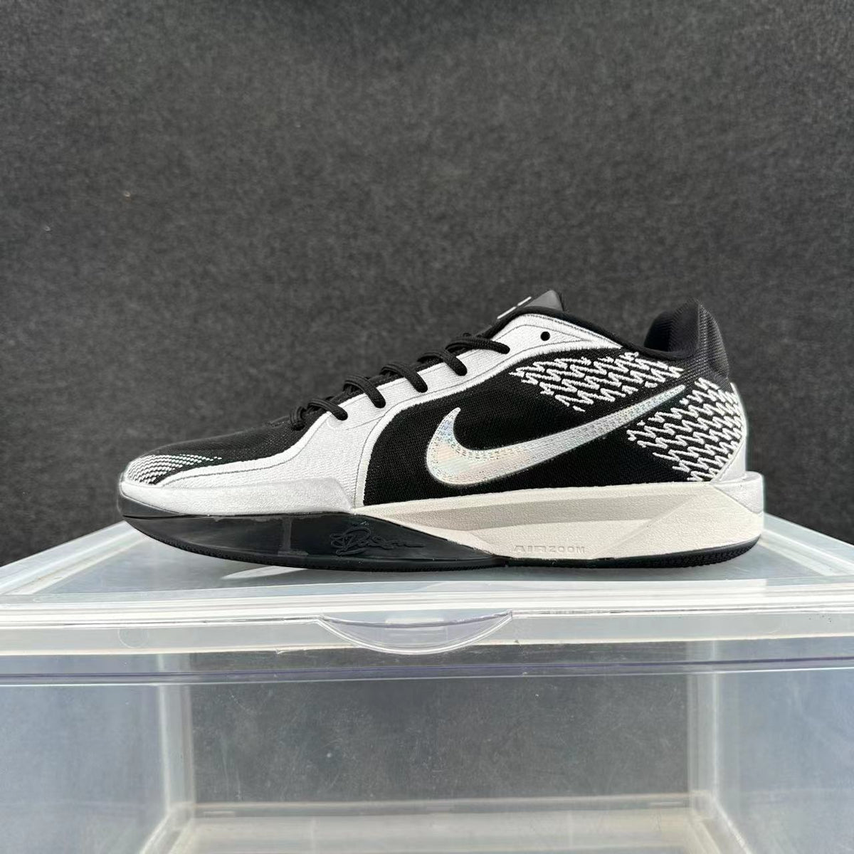 Black and white low-top Nike basketball shoe with a patterned heel, side Swoosh, and sculpted midsole.