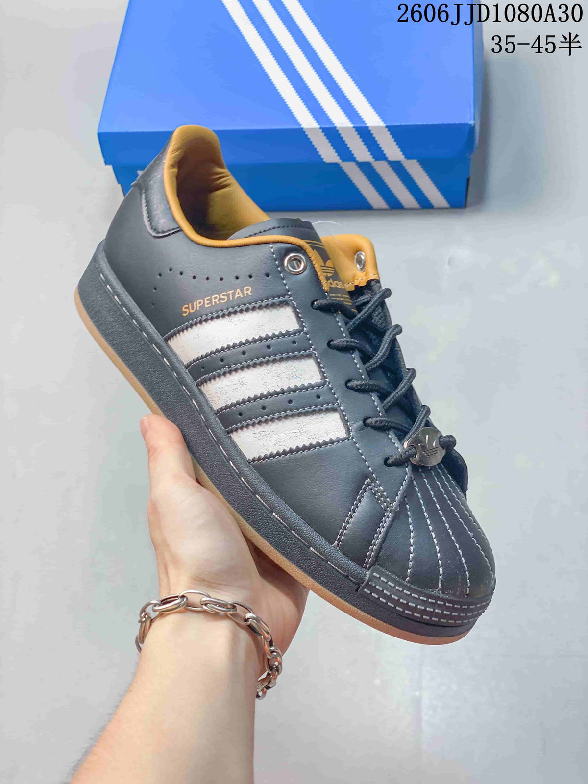 Angled side view of a charcoal adidas Superstar sneaker with contrasting stripes and gold-tone details