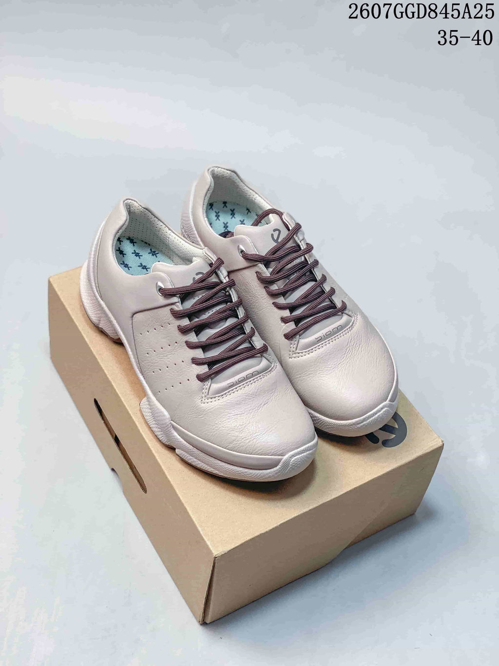 Pair of white ECCO Biom C low-top sneakers displayed on a shoebox, showing the lace-up front, perforated side panels and textured outsole.