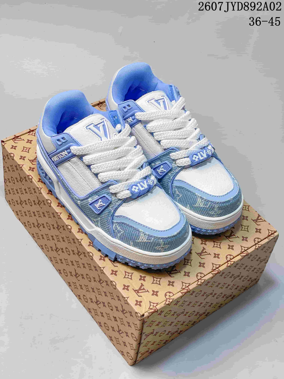 Pair of white and light blue low-top sneakers with white laces on a patterned box