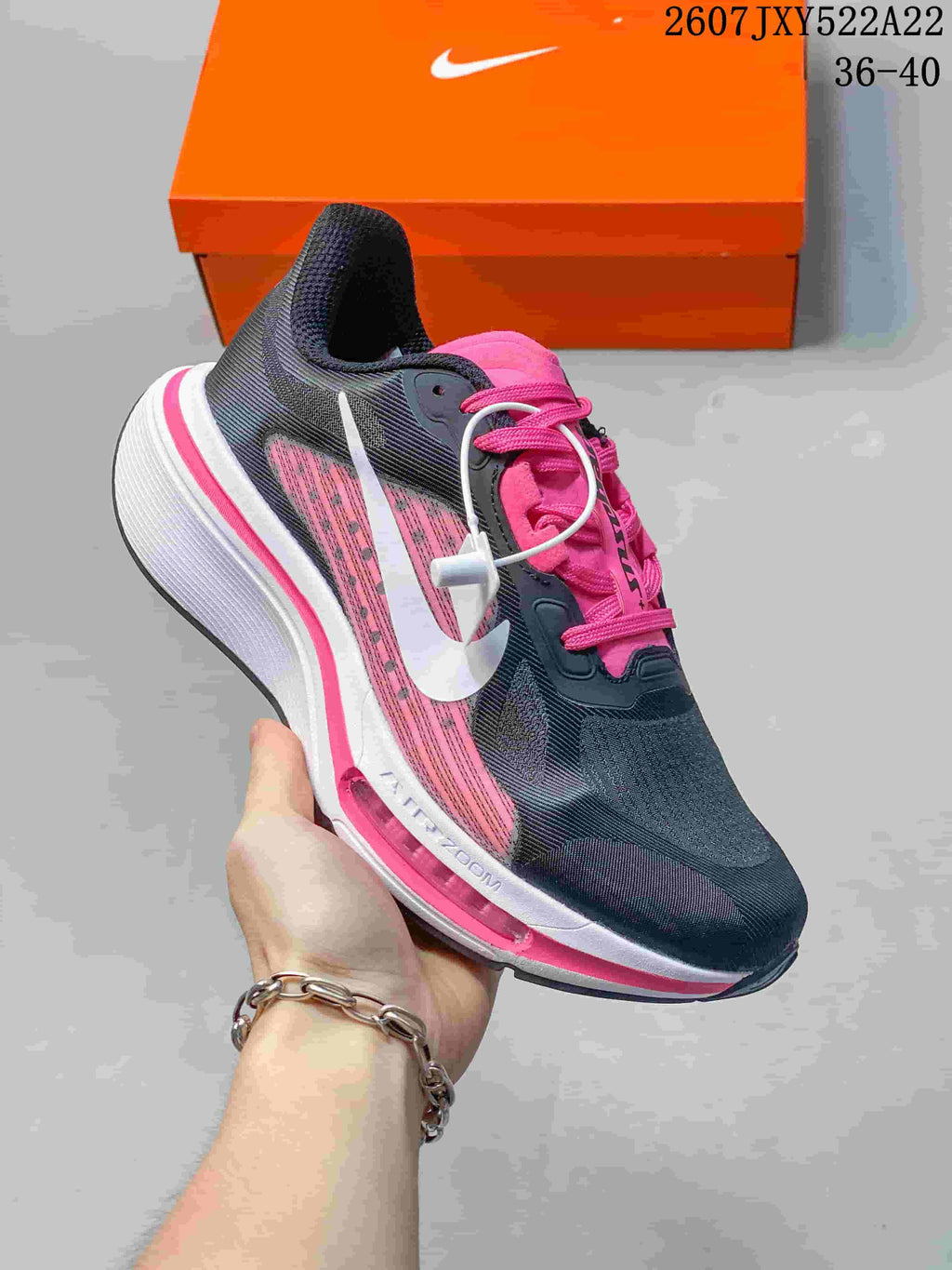 Angled side view showing the black and pink upper, white swoosh, and pink midsole accent.