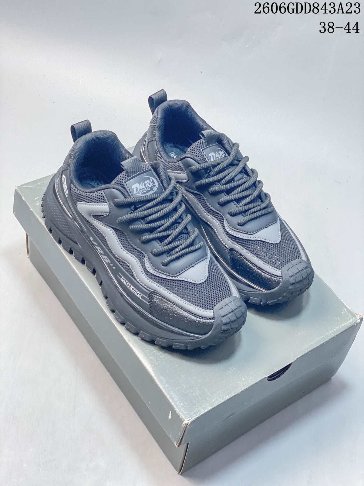 Pair of grey Balenciaga-branded lace-up sneakers with mesh panels and chunky soles on a box.