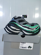 Grey, black and green New Balance sneaker displayed on its box, with the box label visible.