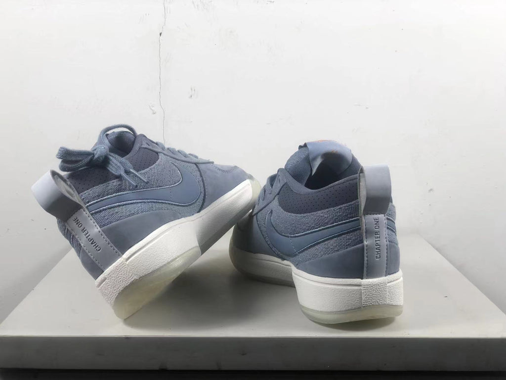 Pair of blue-gray Nike Book 1 shoes shown from the heel, with light-colored midsoles and heel pull tabs.