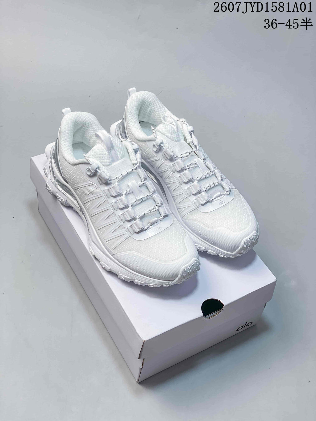 Pair of white Alo Trail sneakers with textured uppers and treaded outsoles.
