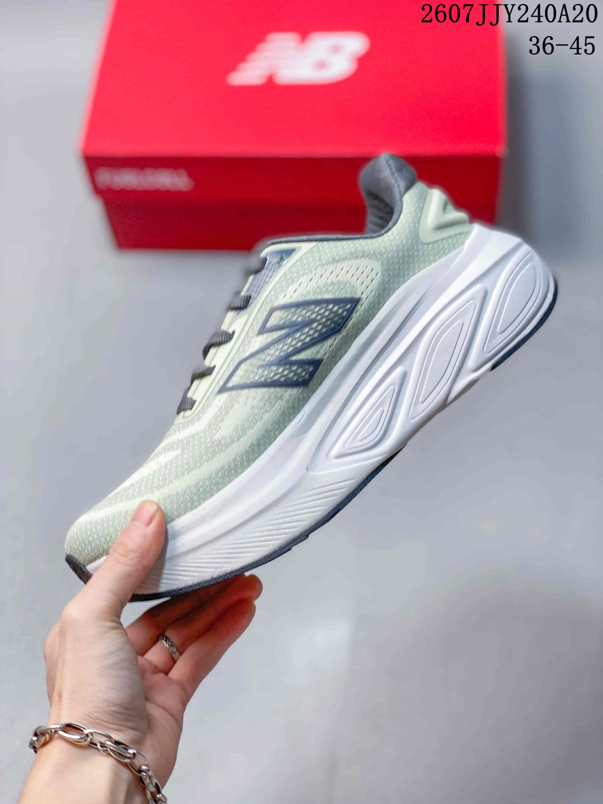 Side profile showing the pale green upper, dark New Balance branding, white midsole, and dark outsole.