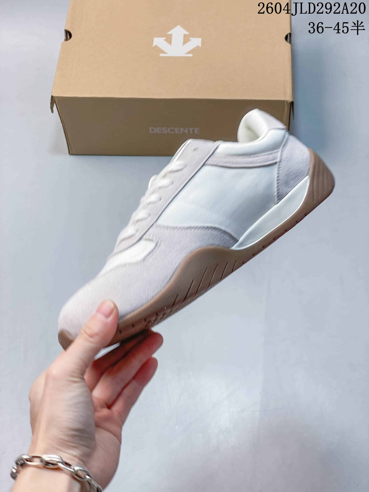 Side profile of a light-colored low-top sneaker with layered panels and a gum-colored outsole.