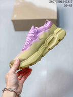 Side view of the sneaker showing the pink and yellow upper, On branding, and chunky textured midsole and outsole.