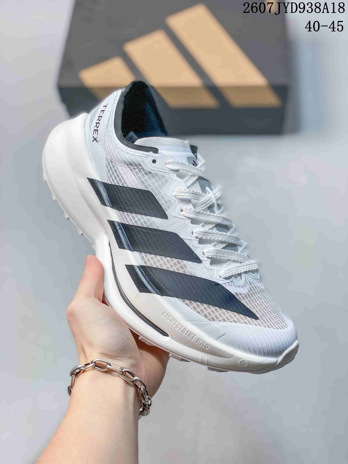 Angled side view of the white and black running shoe, with Adidas stripes, TERREX heel branding and textured outsole visible.
