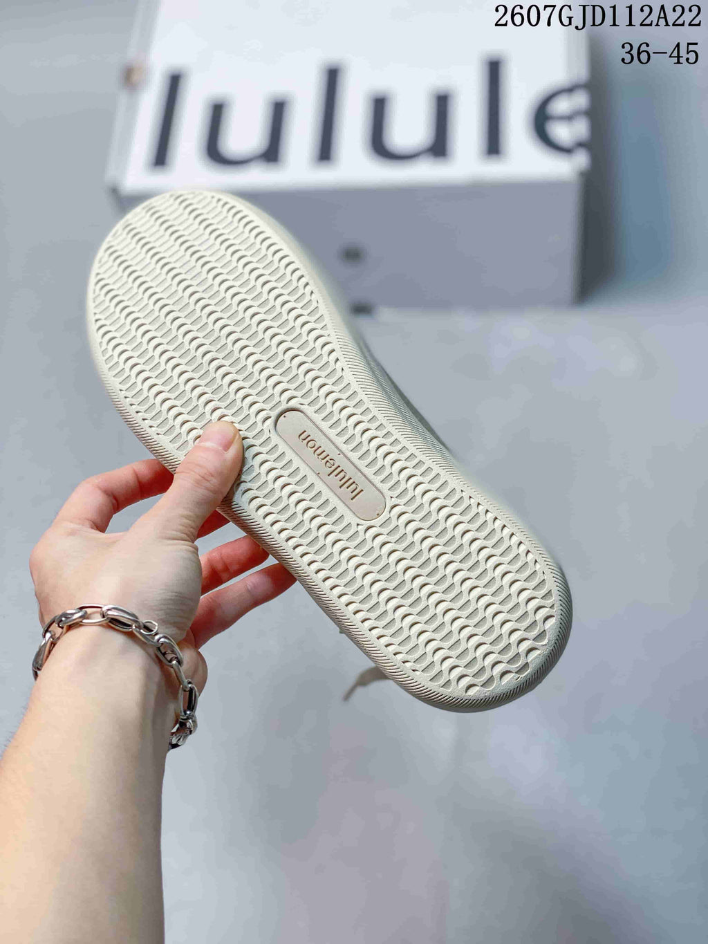 Close view of the patterned outsole of a light neutral lululemon sneaker, showing the textured tread and central branding.