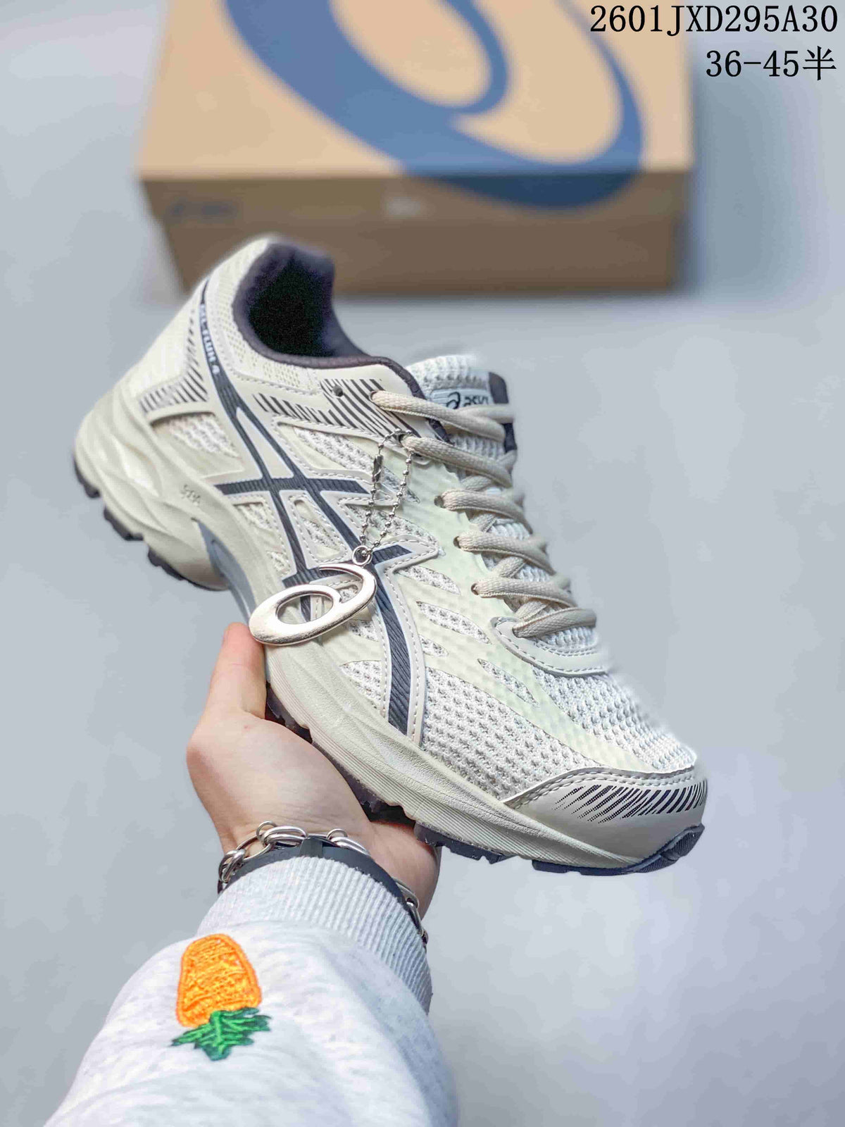 Light-colored ASICS GEL-KAHANA 8 trail shoe with gray-blue accents and a hanging logo charm.