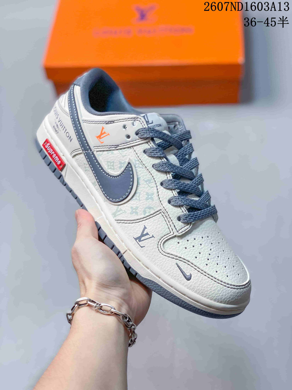 Angled side view of the sneaker showing the white upper, grey Swoosh, printed panels, orange accent mark, and grey outsole.