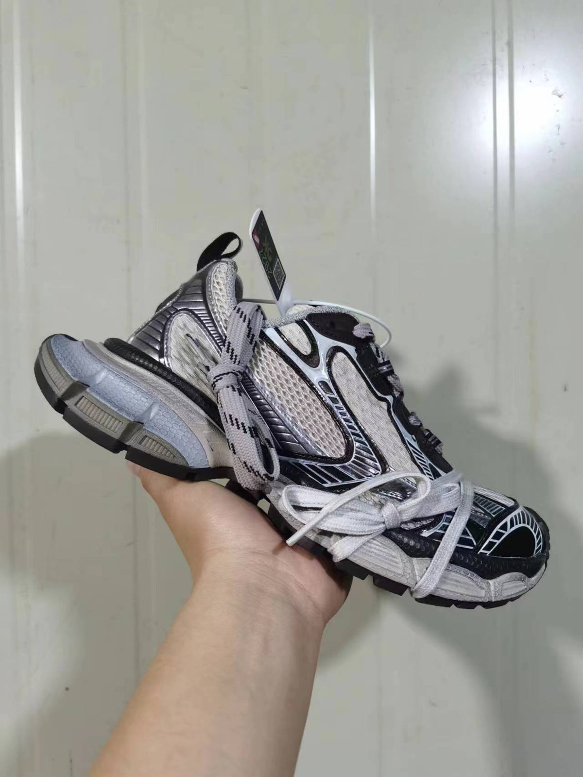 Front and side view of the beige coffee and black sneakers showing layered panels, padded collar, graphic detailing, and chunky outsole.