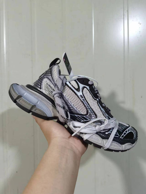 Front and side view of the beige coffee and black sneakers showing layered panels, padded collar, graphic detailing, and chunky outsole.