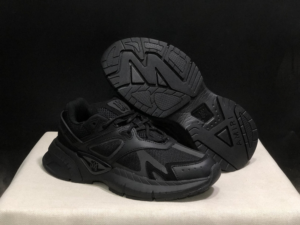Angled view showing the outsole tread pattern and side profile of the black sneakers.