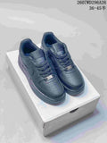 Pair of black low-top sneakers displayed on a shoebox, showing perforated toe boxes, tonal branding, and metal lace tags.