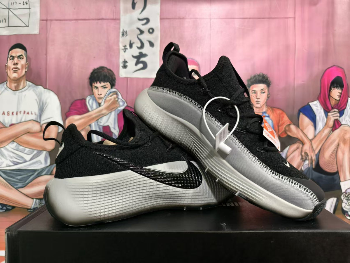 Angled view of a pair of black Nike sneakers with silver-gray side panels and sculpted soles.