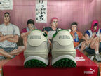 Rear view of off-white and green PUMA sneakers showing branded heel tabs and green outsoles.