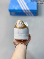 Rear view of a white Stan Smith sneaker with a gold heel tab and embossed branding.