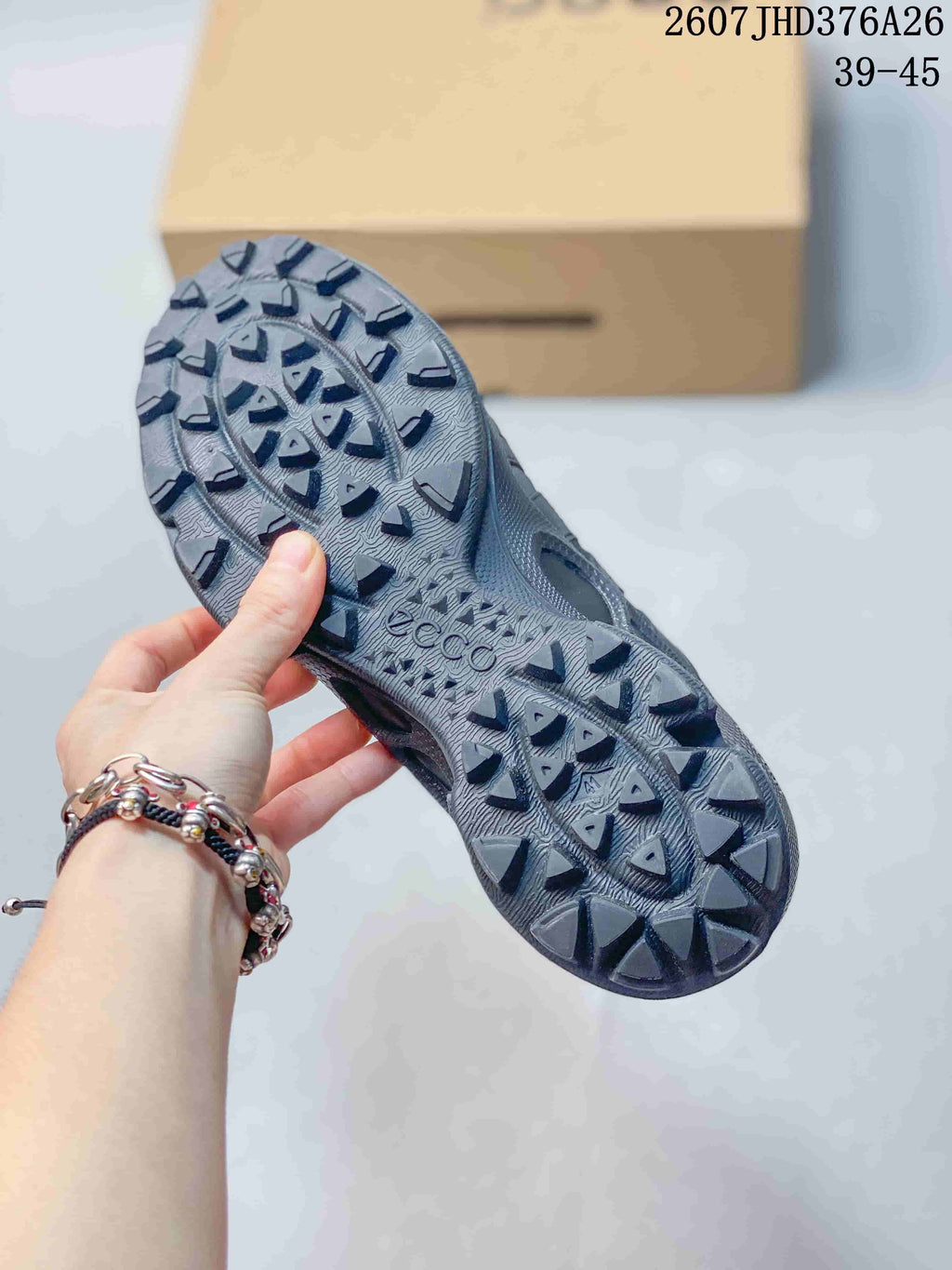 Underside view of a black sneaker showing its textured lugged outsole and ECCO branding.
