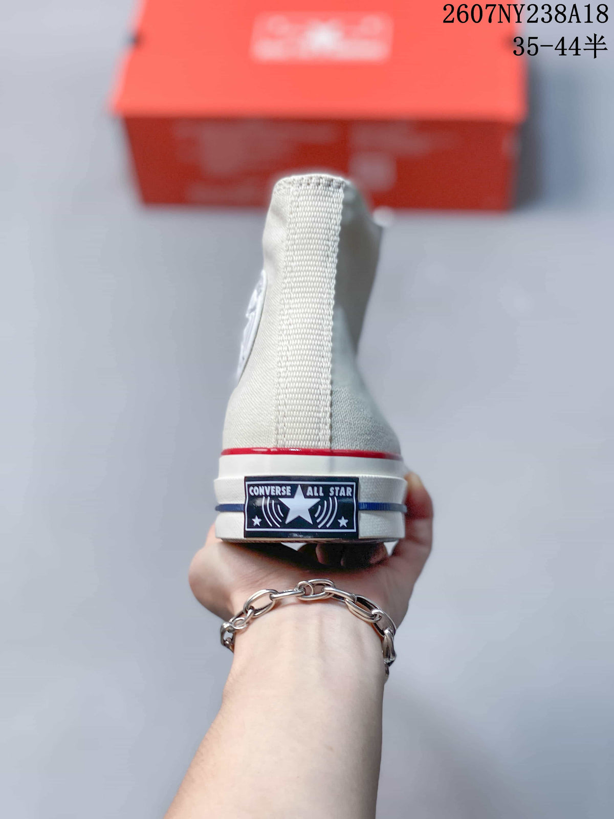 Rear view of an off-white high-top sneaker showing the Converse All Star heel label and layered midsole stripes.