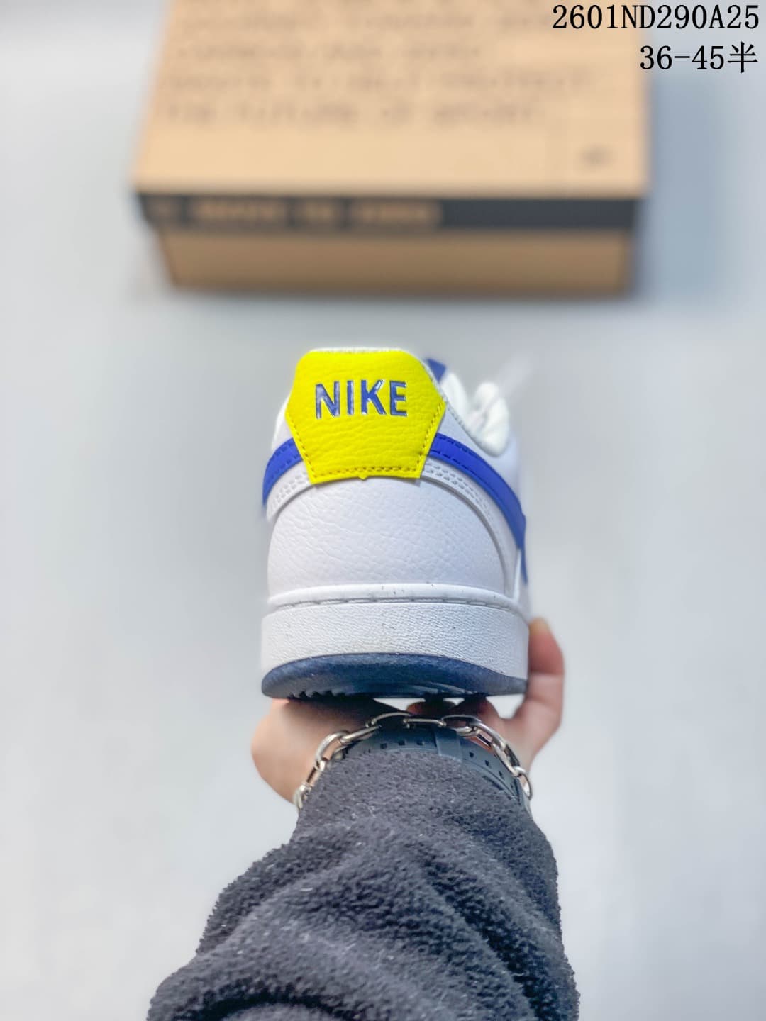 Rear view of the sneaker showing the white heel, blue accent strip, and yellow Nike heel tab.