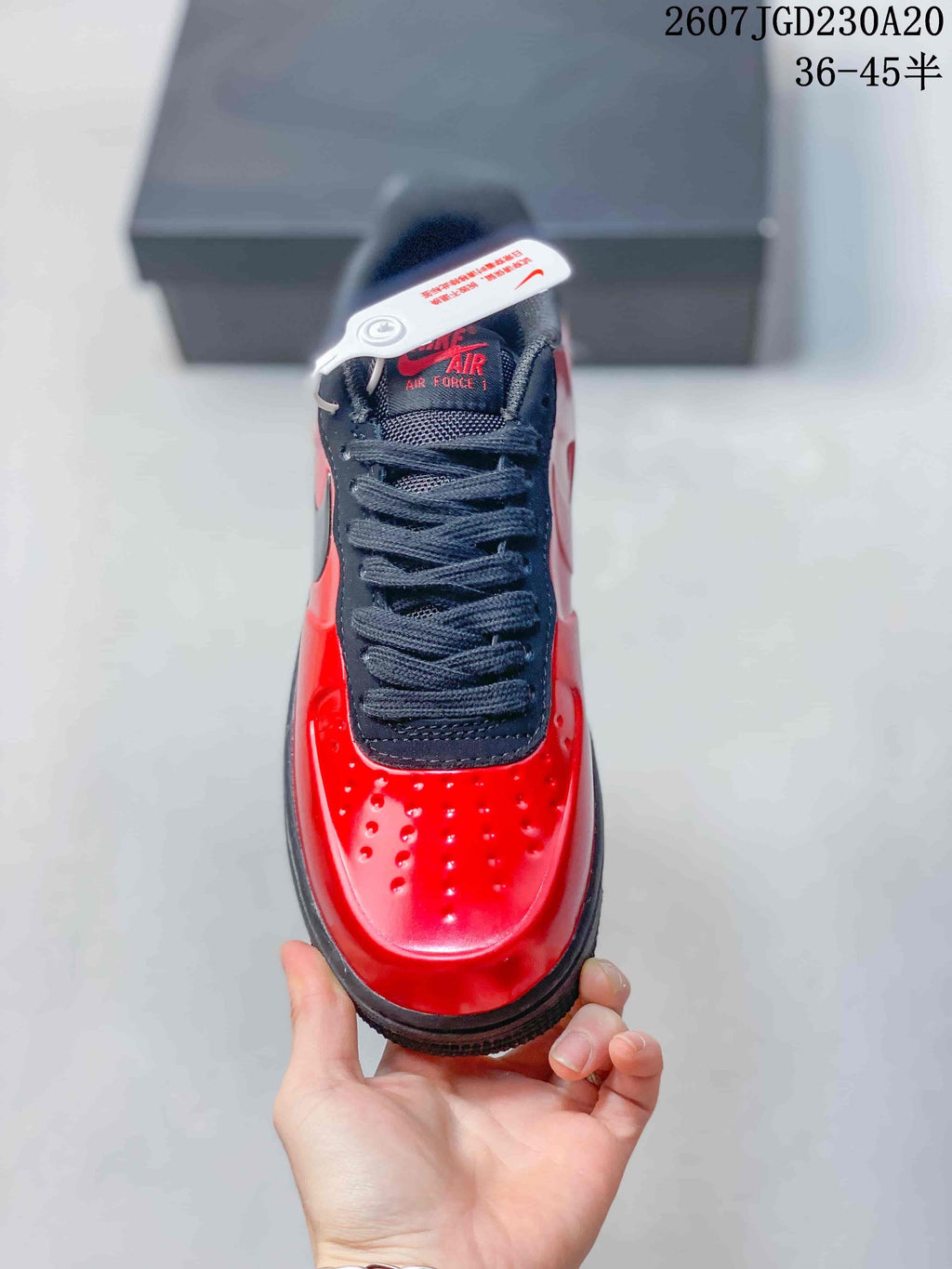 Top view of the sneaker showing black laces, black tongue, red branding, and perforations across the glossy red toe box.
