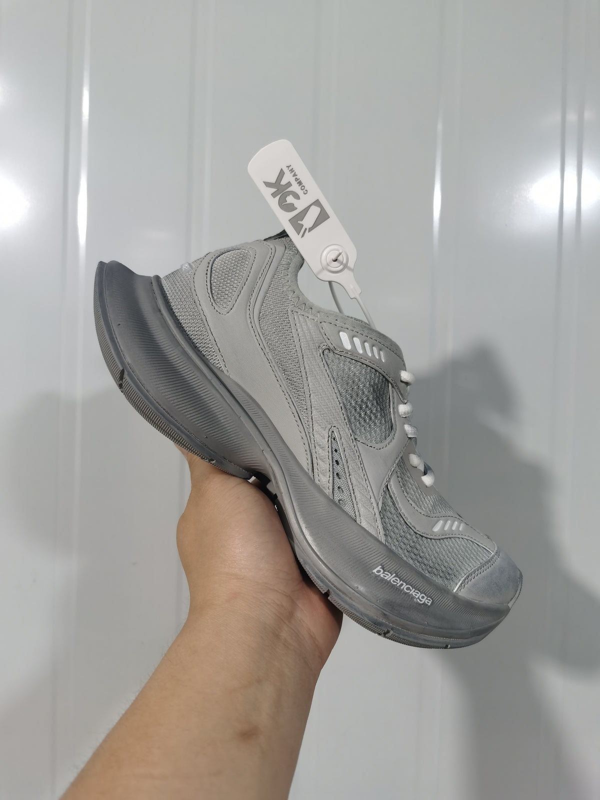 Front three-quarter view of the grey Balenciaga sneaker showing the mesh toe, layered overlays, white laces and branded sole.