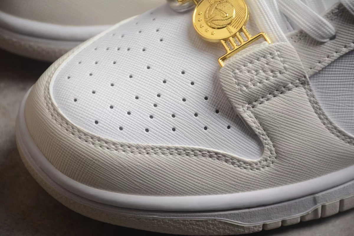 Close-up of the perforated white toe box, layered off-white overlay, and gold-tone clasp.