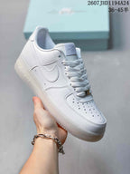 Angled side view of the white Nike sneaker showing the perforated toe, Swoosh and translucent sole.