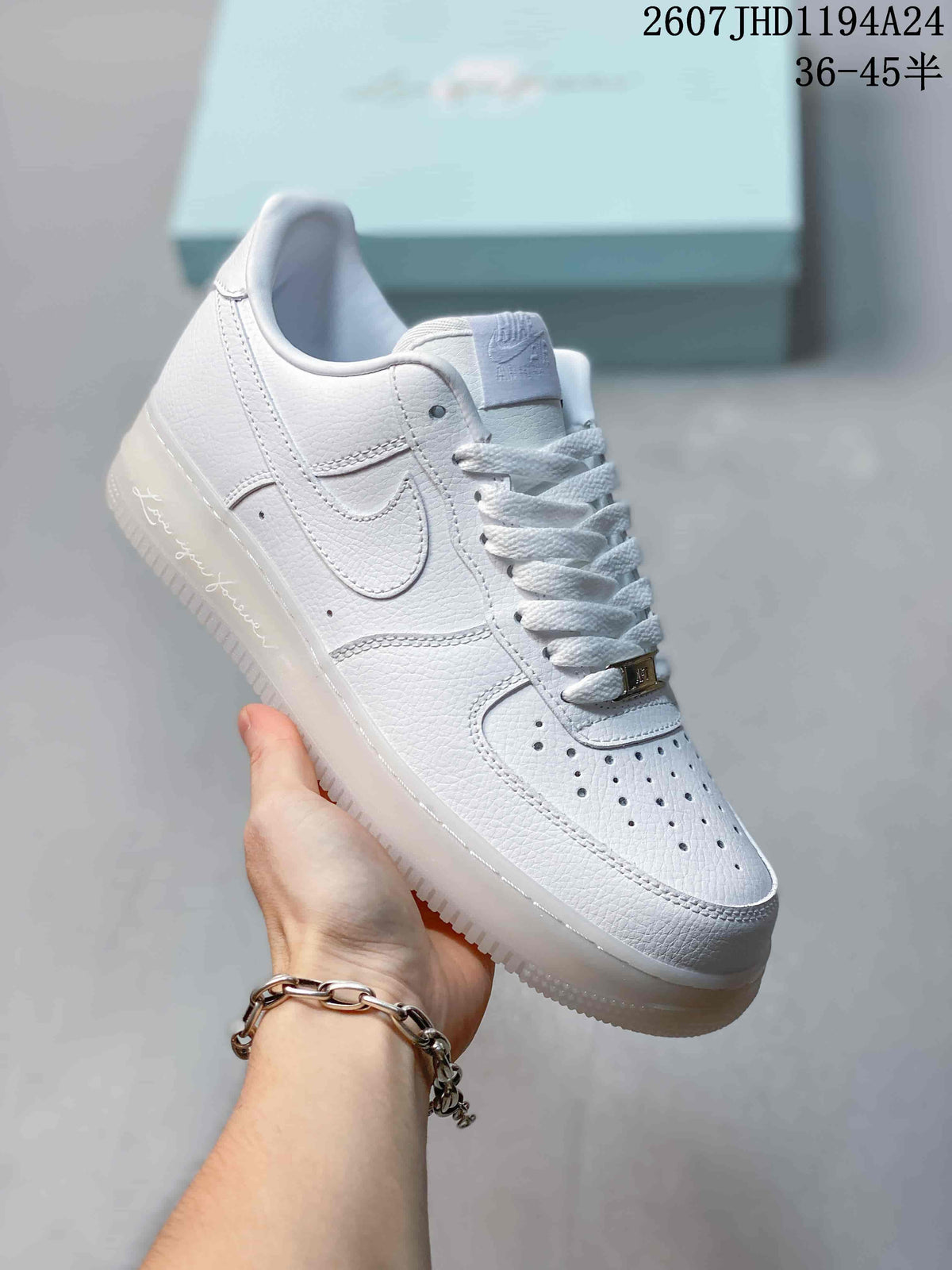 Angled side view of the white Nike sneaker showing the perforated toe, Swoosh and translucent sole.