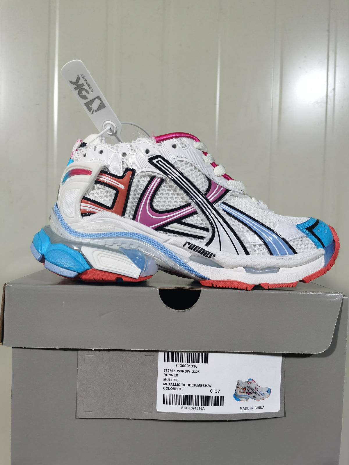Multicolor Balenciaga Runner sneaker displayed on its box, showing the white mesh upper, colored overlays and layered sole.