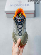 Top view of the sneaker showing black laces, olive textile panels, orange collar lining and round toe.