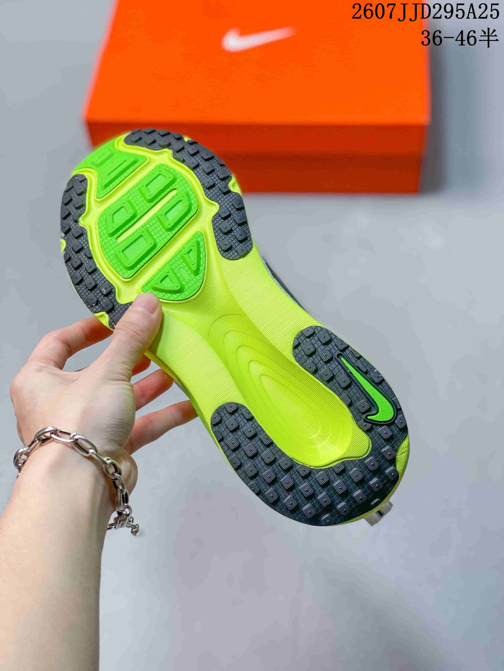 Close view of the neon green and black outsole with segmented traction pattern, with an orange Nike shoe box in the background.