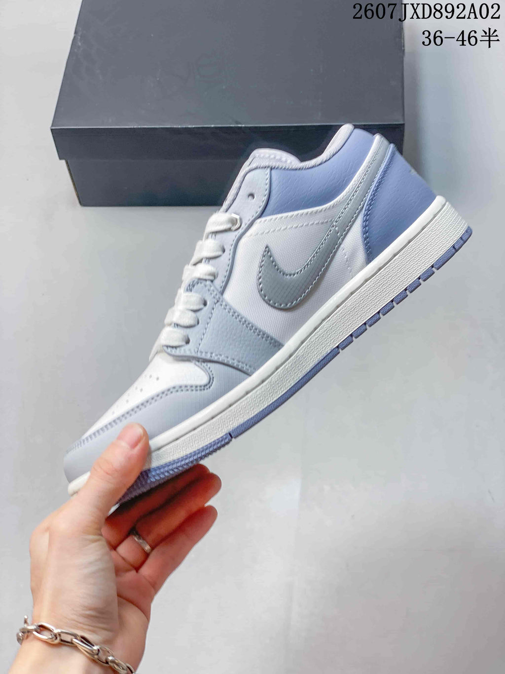 Side view of the low-top sneaker with white panels and blue-gray overlays.