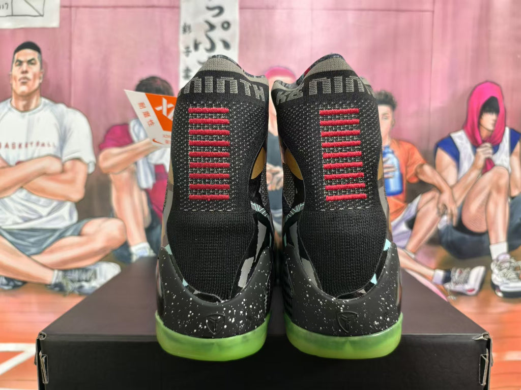Rear view of black high-top basketball shoes with red heel detailing and green outsoles
