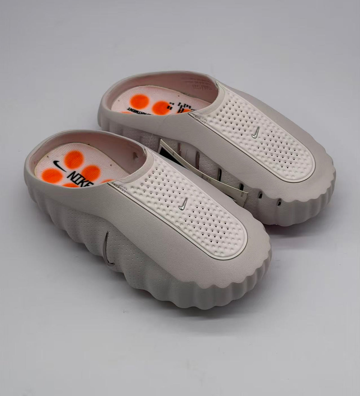 Top view of the pair showing perforated straps, pink footbeds, orange circular graphics, and Nike branding.