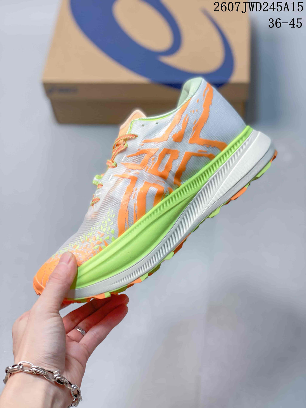 Side view of the sneaker showing orange ASICS branding, a white mesh-style upper and raised lime-and-white midsole; image text shows code 2607TWD245A15 and sizes 36–45.
