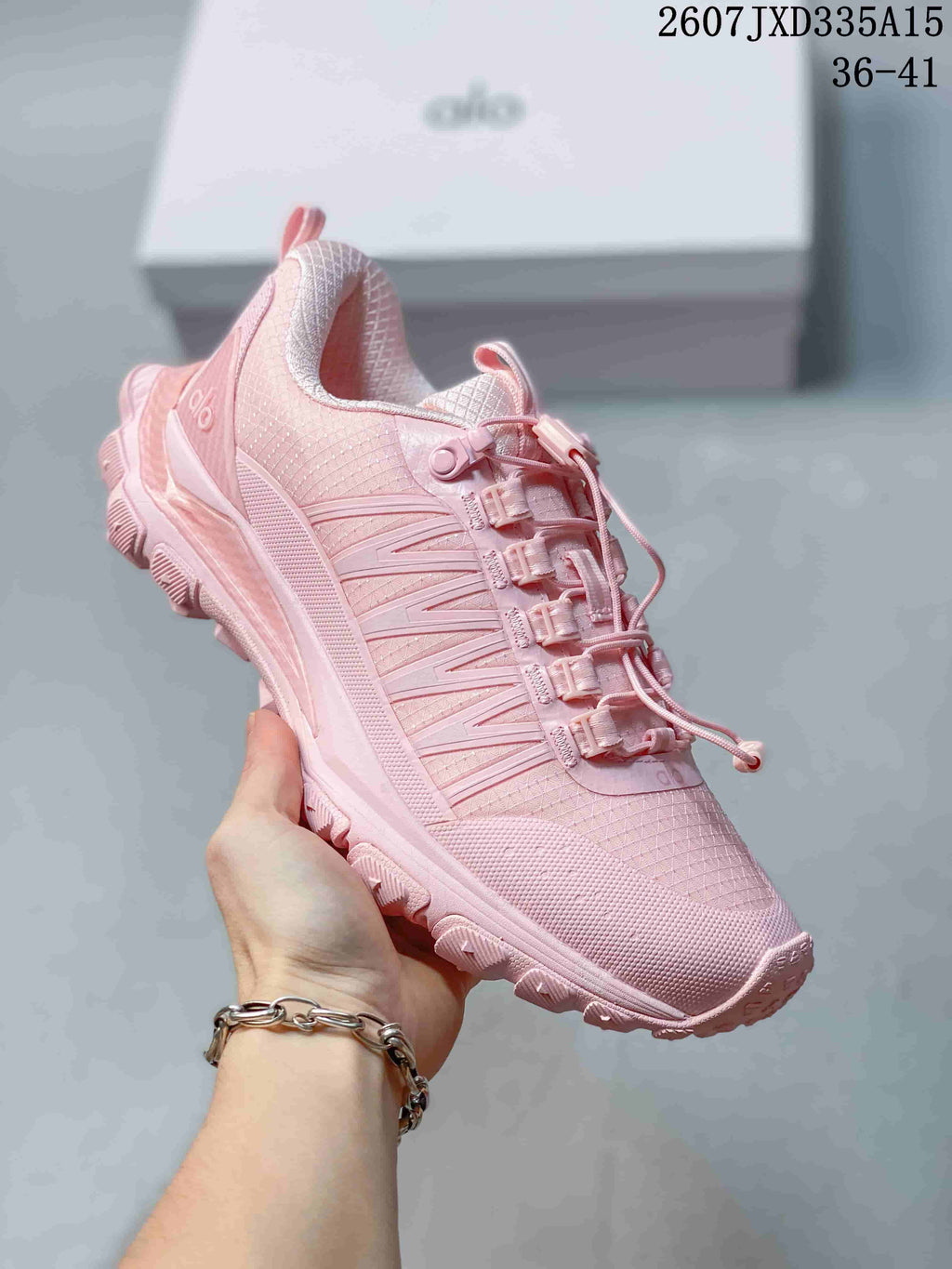 Angled side view of the pink Alo Yoga sneaker showing the layered side design, padded collar and textured upper.